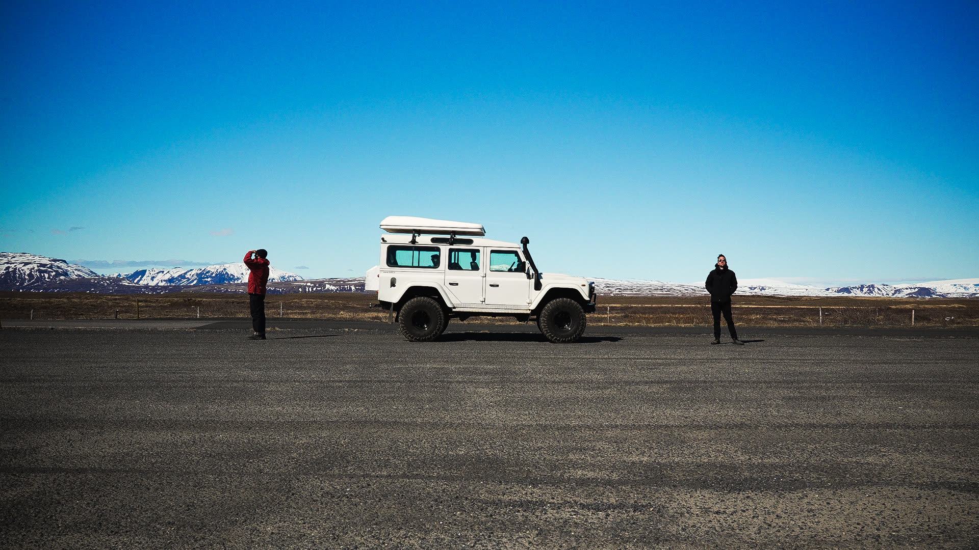 All The Gear presenters either side of a Land Rover Defender on an Icelandic road